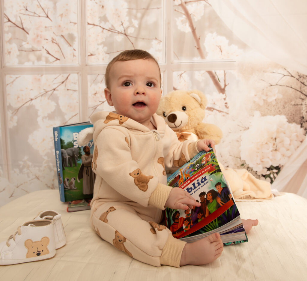 Toddler holding a book in a onesie